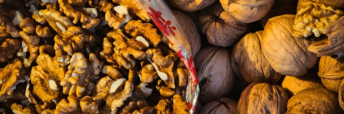 A rustic pile of raw, brown walnut kernels, showcasing their intricate, brain-like texture and earthy appeal.