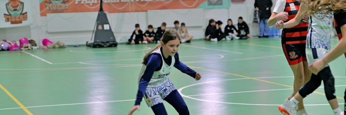 A girl dribbling a basketball on a green indoor court during a game